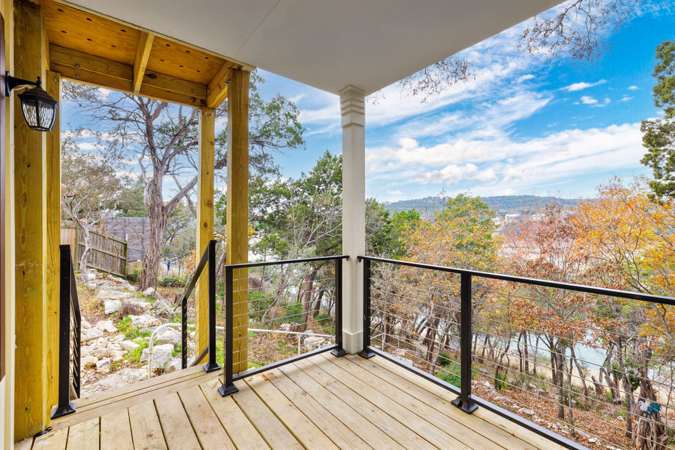Transitional outdoor remodel in Austin, TX featuring a hillside deck addition with cable railing, natural wood flooring, and breathtaking Lake Travis views.