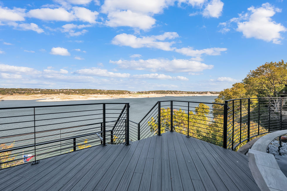 Open-air landing zone with sleek black railing and wide lake vistas, part of a contemporary multi-level deck renovation in Austin, TX.