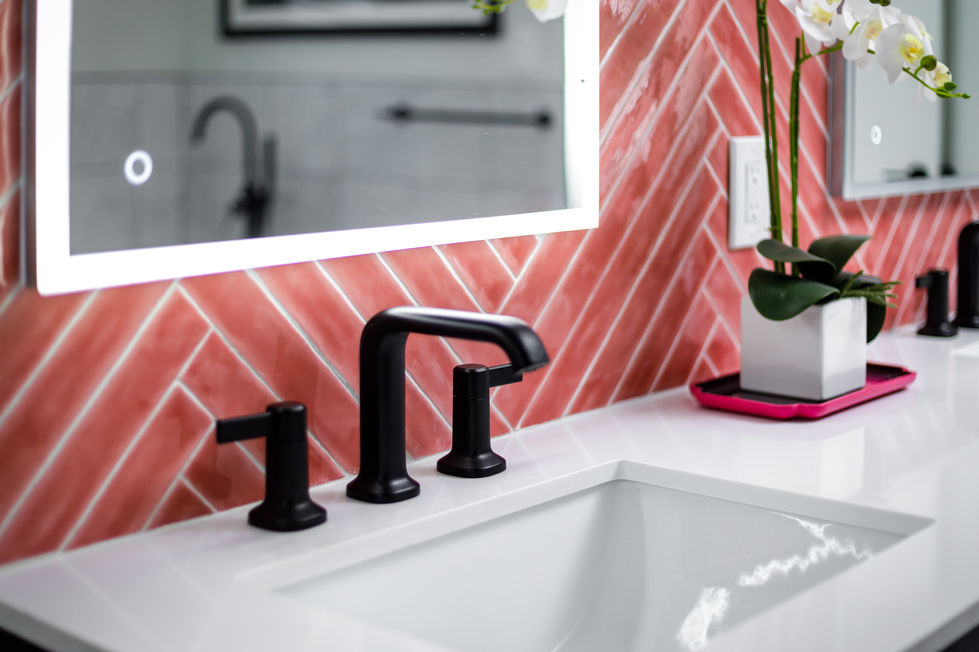 Modern bathroom sink remodel with matte black fixtures, white quartz countertop, and high-gloss coral herringbone tile accent wall, blending exotic materials and vibrant design elements in Austin, TX.