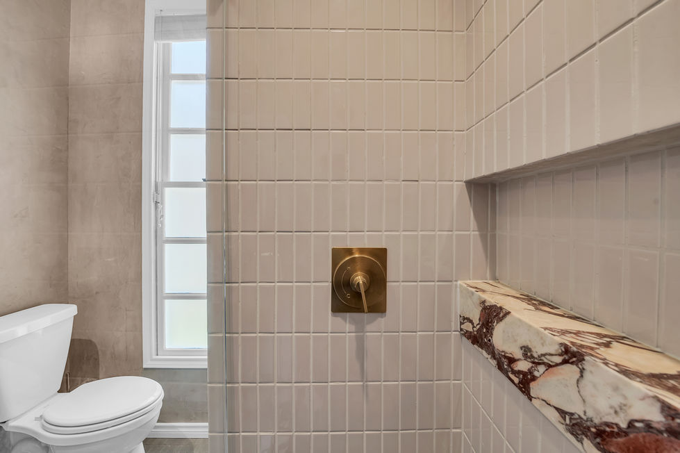 Walk-in shower with vertical stacked tile, custom marble niche, and brass fixtures in Austin bathroom renovation.