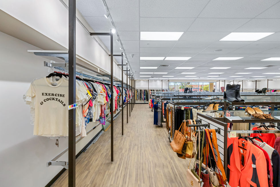 Retail remodeling in Austin, TX featuring a long aisle layout with modern industrial pipe racks, track lighting, and light wood flooring.