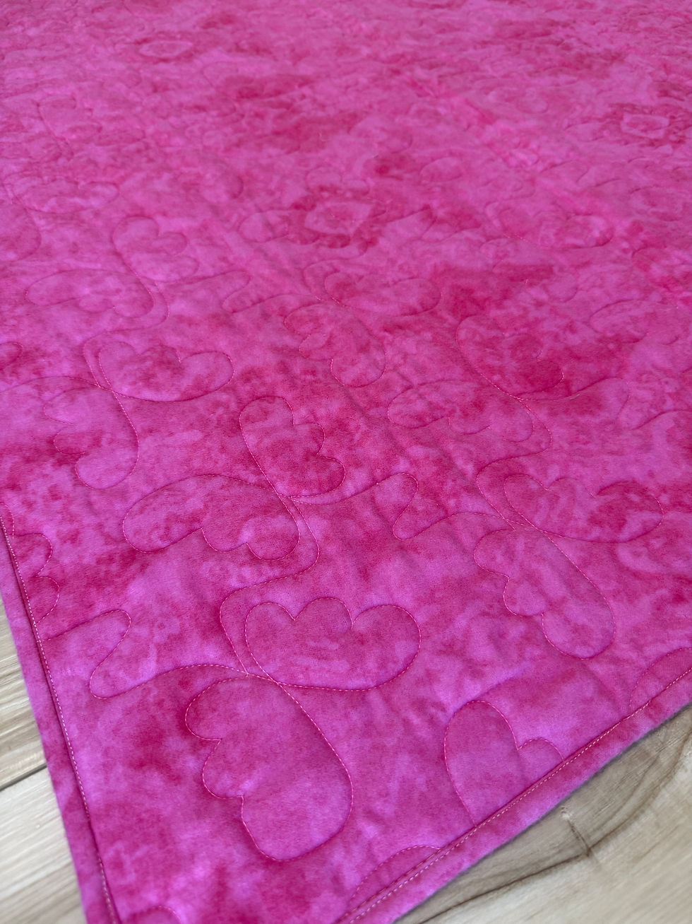 Thumbnail: Soft pink flannel baby quilt with multicolored bubble print and darker pink binding and backing with butterfly quilting