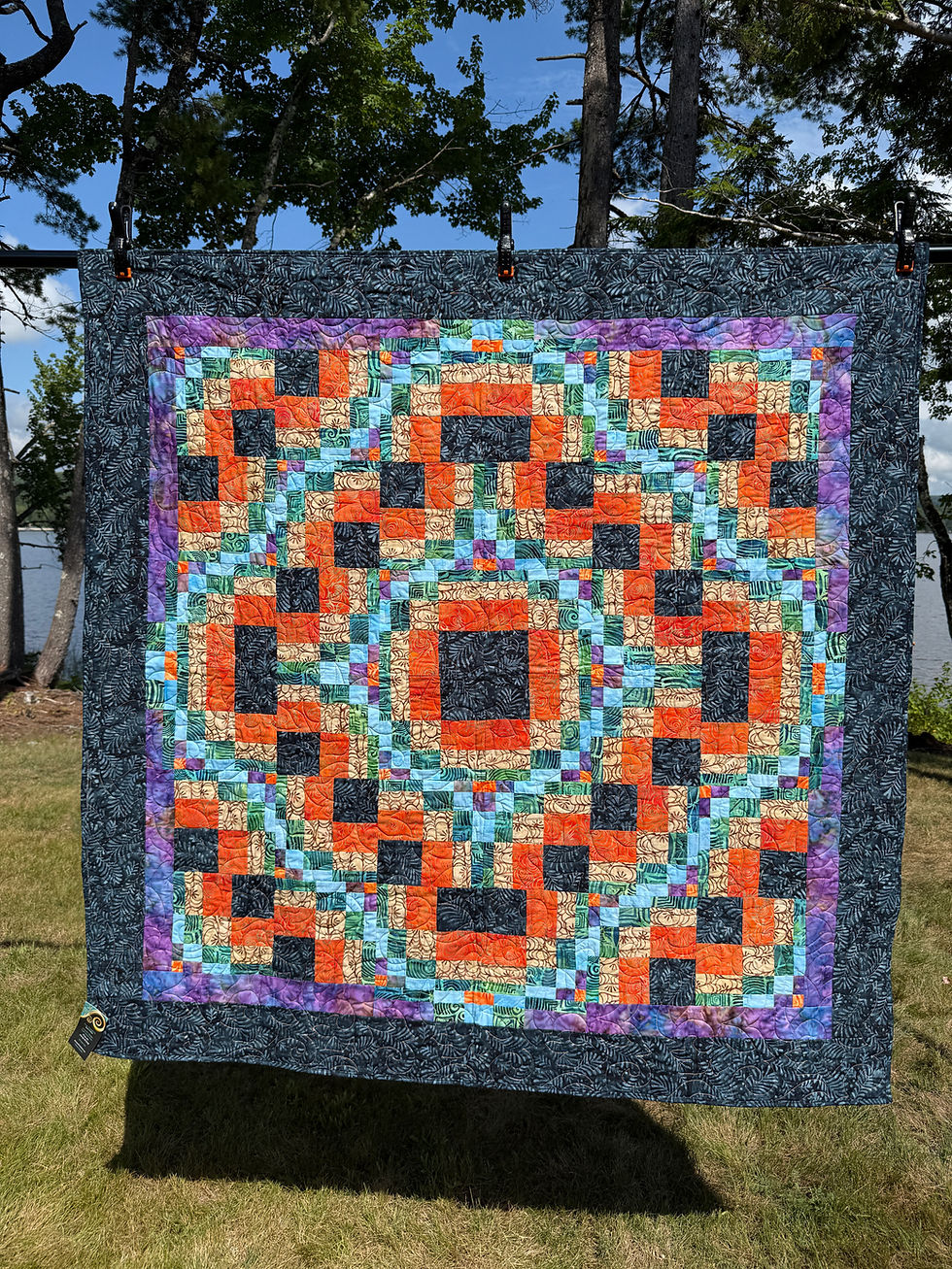 Throw quilt with bargello-style interlocking blocks in orange, black, tan, aqua, and green batiks