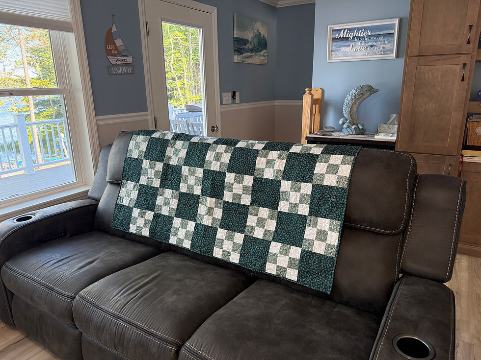 Handmade lap quilt with nine-patch blocks in teal, cream, gray, and beige arranged in a checkerboard pattern.