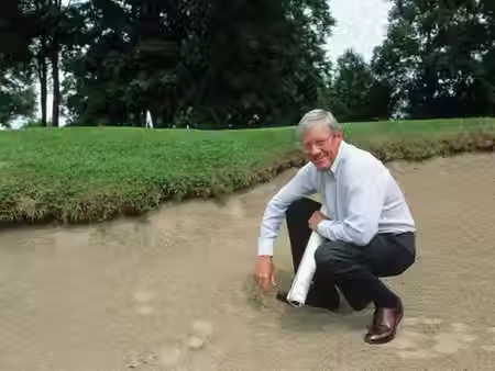 Arthur Hills sitting in a sand trap on a golf course