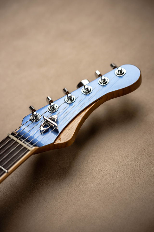 Detail shot of a blue and brown guitar headstock, close-up view