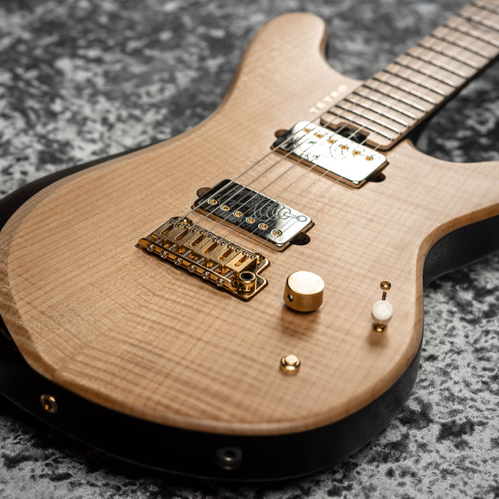 Wooden electric guitar with metal hardware on a textured grey background