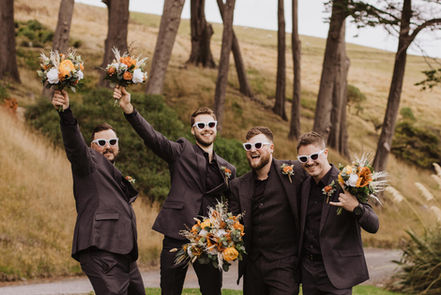 groomsmen holding flower bouquets