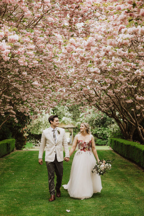 Bide and groom walk hand in hand with the blossom at the Hideaway 201