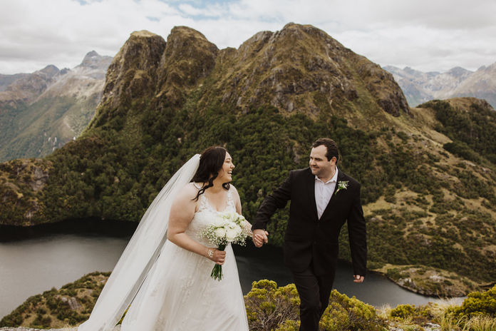 Bride and groom walk hand in hand at the North West Lakes in Fiordland