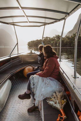 Bride and groom in a boat heading to a waterfall in New Zealand