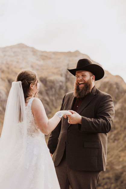 groom laughing with bride on top of a mountain