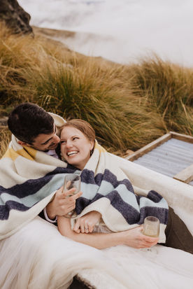 Bride and groom cuddled up in a blanket with wine