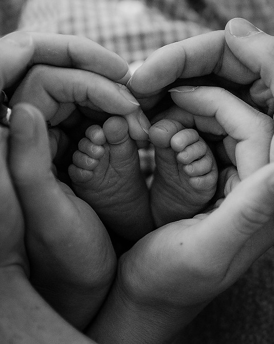 A closeup of newborn toes with the parents' hands around it during a lifestyle newborn session in Morgantown, WV