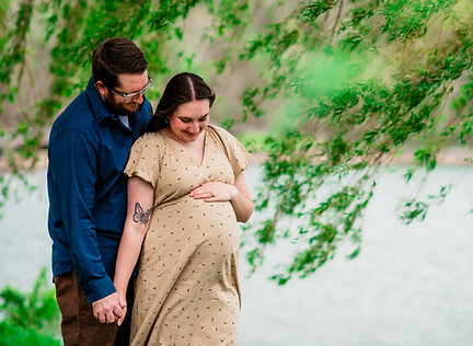 An expecting couple poses by a willow tree beside Cheat Lake, Morgantown, WV during a maternity portrait session.