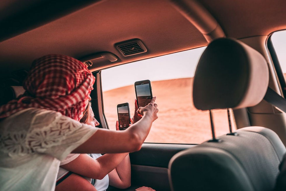 People holding phones towards a car's window as they pass by a safari