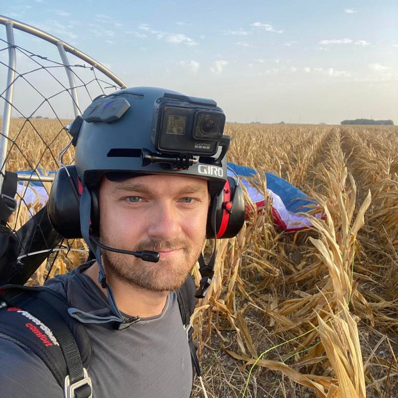 Joe Orsi wearing a paramotor helmet after landing in a corn field