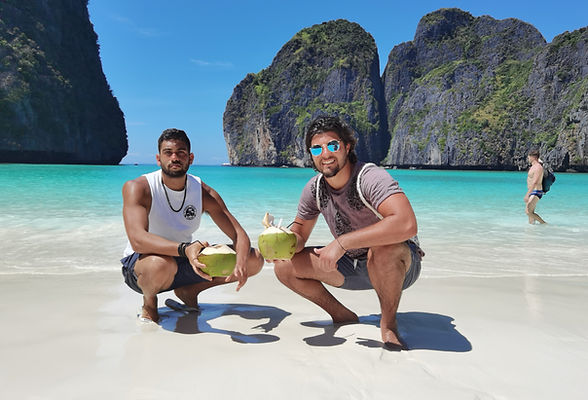 Two men posing at Maya Bay beach in Koh Phi Phi with turquoise sea water.