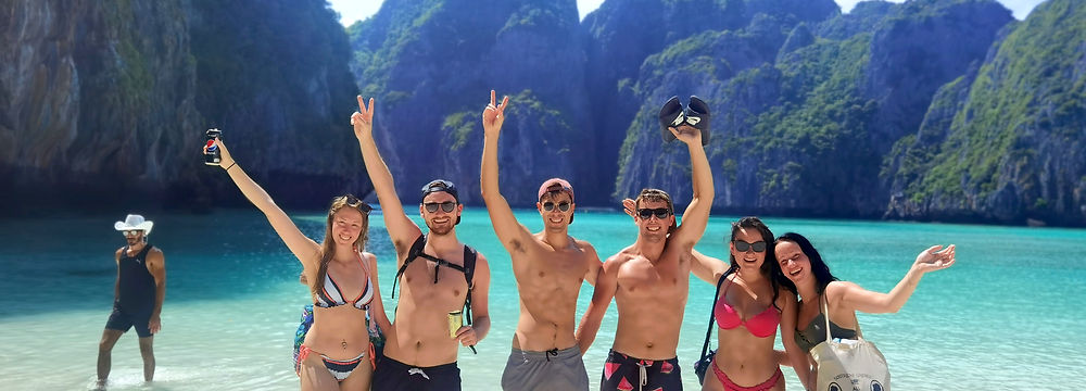 Four women posing at Maya Bay beach in Koh Phi Phi with turquoise sea water.