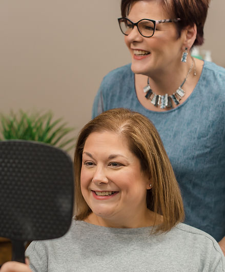 Happy woman at radiant roots checking hair, with kristi's assistance
