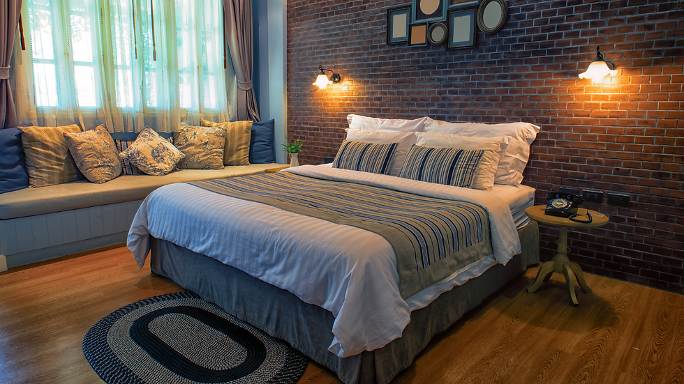 Cozy bedroom with a brick accent wall, a bed with striped pillows, and a vintage phone on a wooden side table. Soft natural light.