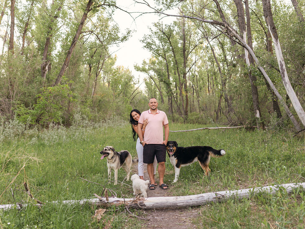 Jen and Logan stand in a woodsy area with their dogs; one is Fynn, adopted from New Hope Dog Rescue.