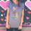 Thumbnail: Model is wearing a light gray t-shirt with the balloon girl image standing in front of a spray painted wall with pink & red hearts