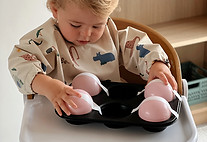 Boy aged 18 months doing a kids activity with balls, washi tape and a muffin tin