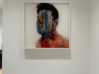 a framed painting of a man 's face is hanging on a white drywall