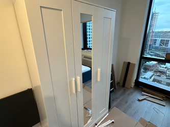 a white wardrobe is being assembled in a bedroom
