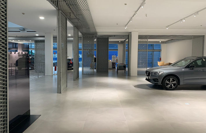 Area espositiva interna Volvo con automobile, illuminazione a binario e pavimento chiaro.