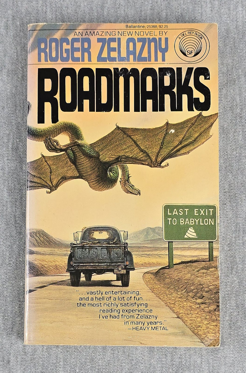 Cover with pickup truck driving down a winding road beneath a flying dragon with highway sign reading Last Exit to Babylon.