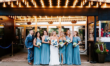 A group of bridesmaids surrounding the bride in front of the Lyric Theater.