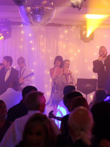 AURA Showband performing to a full dance floor at a luxury wedding party with live vocals and stage lighting.