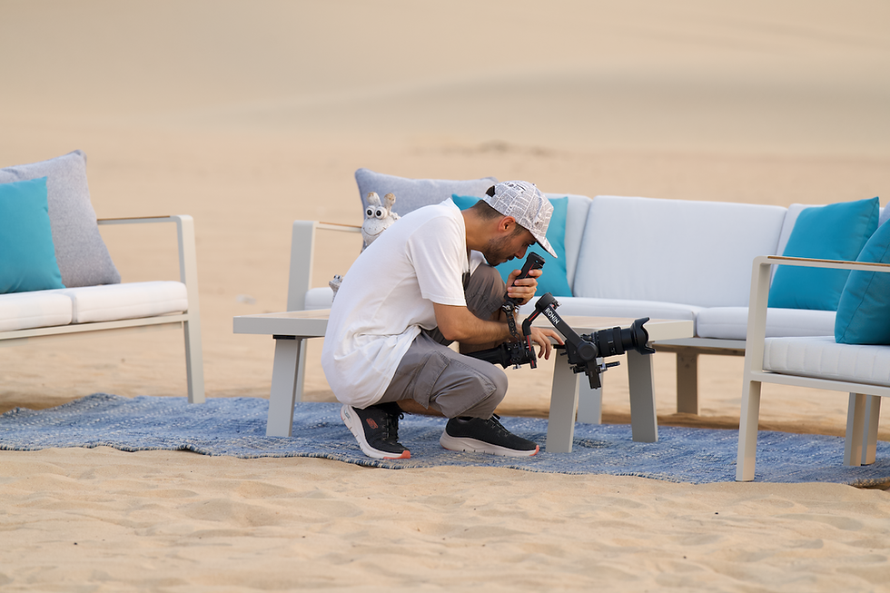 HyperJump Productions' Head of Camera, Sid Sampat, crouches to shoot some of Suncoast's furniture in the Al Qudra desert.