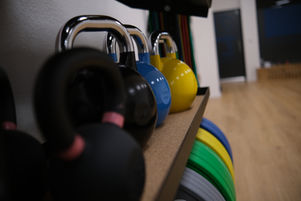 5 Kettlebells und mehrere Hantelscheiben im Regal