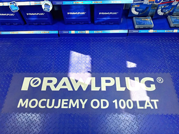 RAWLPLUG: MOCUJEMY OD 100 LAT banner on a blue floor. FLOORA.