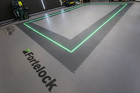Fortelock logo and flooring with a green border, garage setting. FLOORA