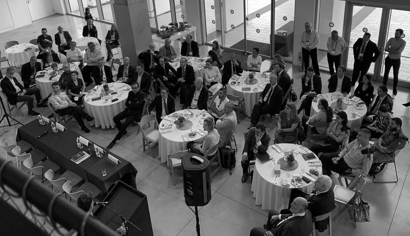 Attendees at a formal event, seated at tables and standing.