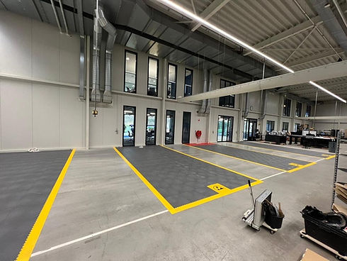 אולם תצוגה גדול עם חניות מסומנות בצבע צהוב וציפוי ר�צפה. FLOORA