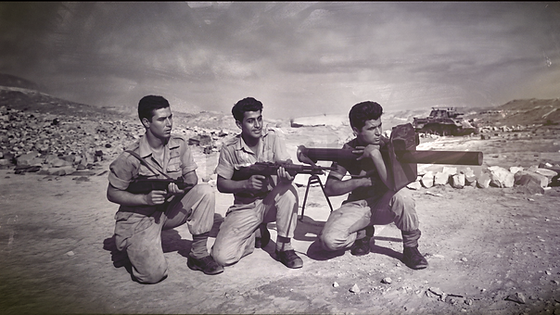 שלושה לוחמים כורעים עם נשק בשטח פתוח, תמונה היסטורית