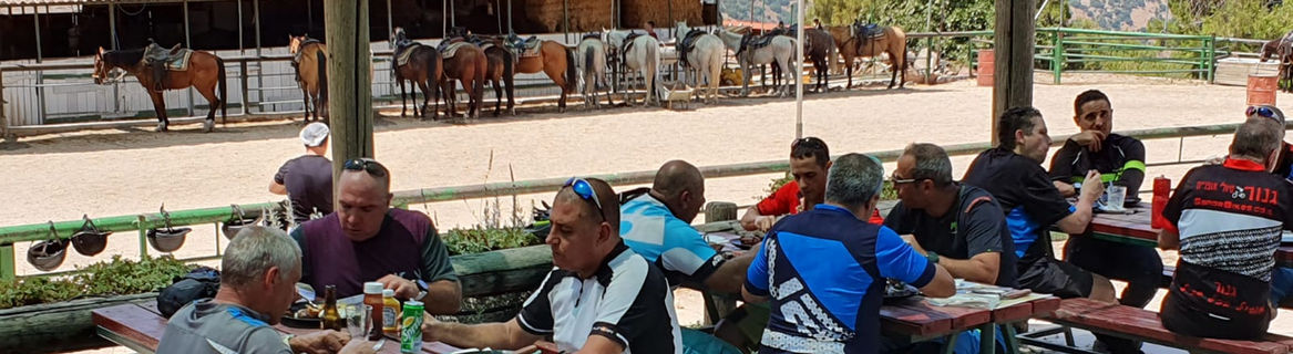 קבוצת אנשים אוכלת בחוץ ליד אורוות סוסים.