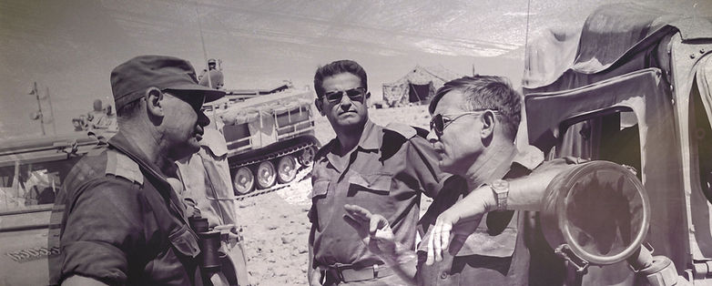 שלושה קציני צה"ל בשיחה בשטח צבאי לצד רכב משוריין