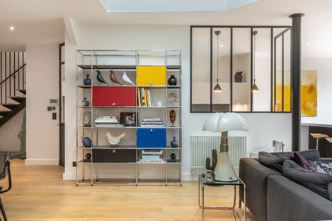 Bibliothèque USM multicolore et mobilier iconique dans un salon à la fois sobre, graphique et chaleureux.