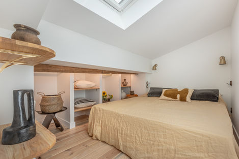 Suite parentale sous les toits, poutres apparentes, mobilier naturel et tons apaisants pour une atmosphère authentique.