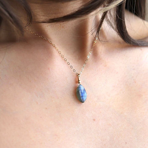 Wearing a unique Labradorite smooth marquise gold necklace, high-quality artisan gemstone, glowing sparkling blue light