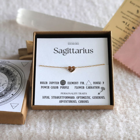 Sagittarius anklet with a heart charm on display card detailing attributes like ruler: Jupiter, element: fire.