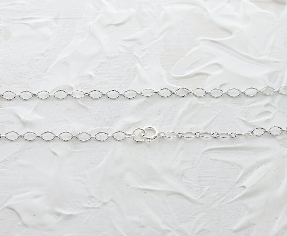 Silver chain links on textured white background, featuring a delicate clasp in the center. Simple and elegant design.