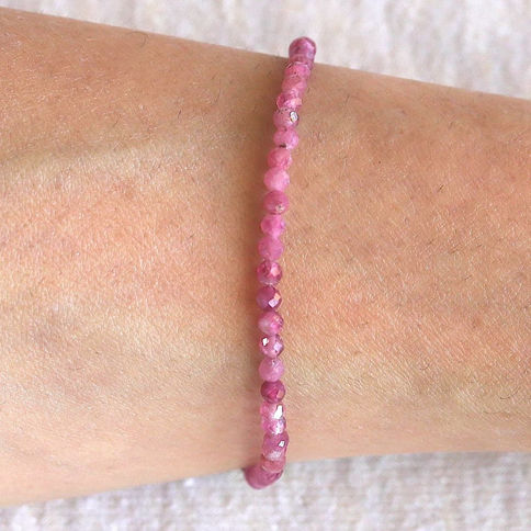 Pink tourmaline beaded bracelet on a wrist with a soft background. The bracelet features small, round, faceted beads, creatin