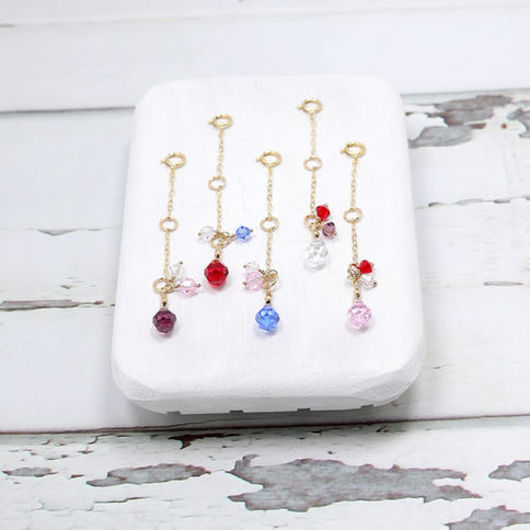 14k gold filled necklace extenders with colorful rhinestone beads displayed on a white surface with a rustic background